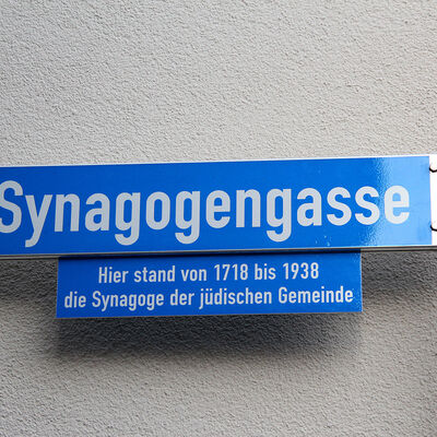 Straßenschild der Synagogengasse in Flörsheim am Main mit dem Zusatztext: Hier stand von 1718 bis 1938 die Synagoge der jüdischen Gemeinde